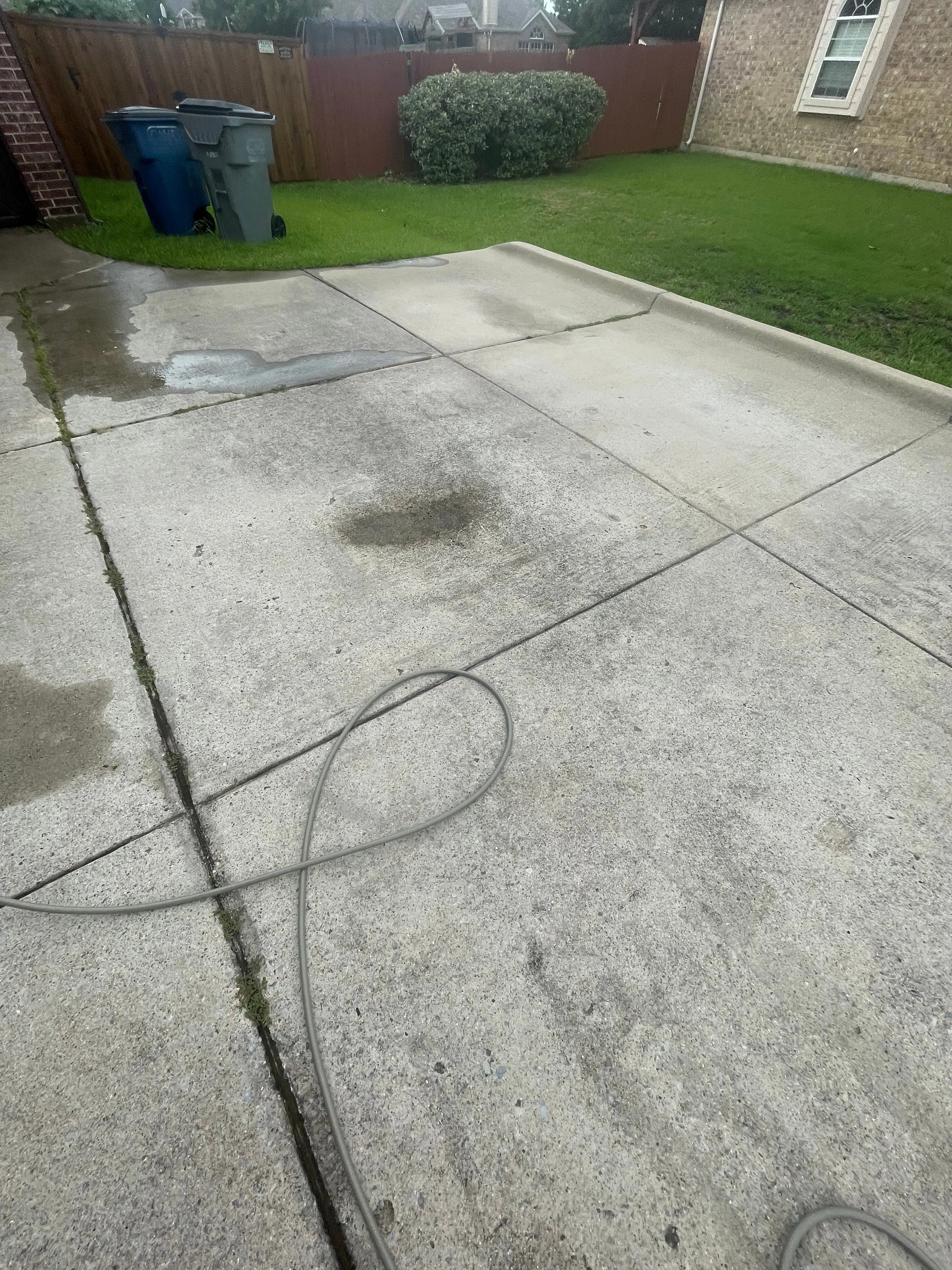 Stained patio concrete with algae and an oil spot before power washing in Wylie, TX