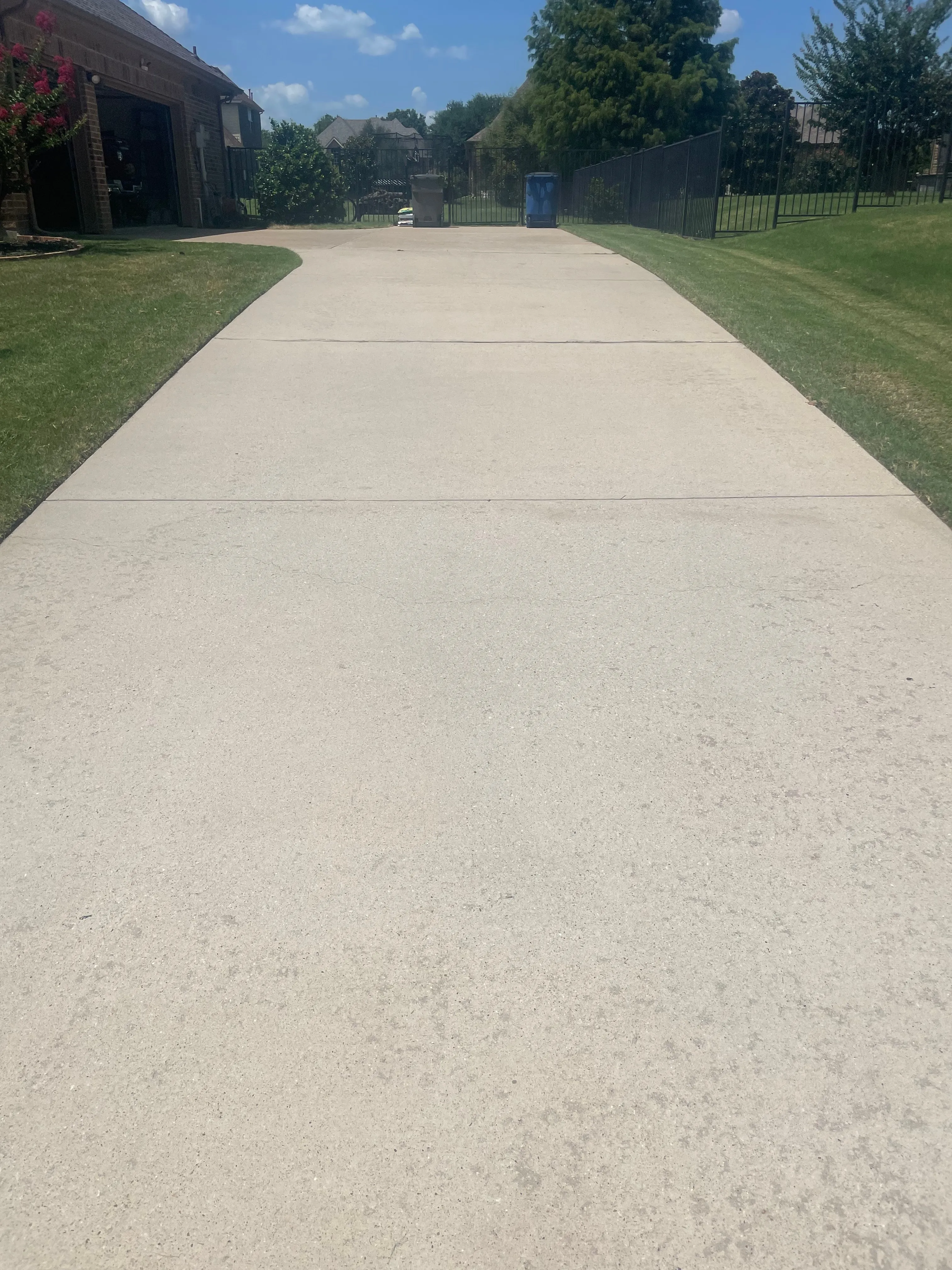 The same long driveway cleaned to bright, even concrete after pressure washing in the Dallas area