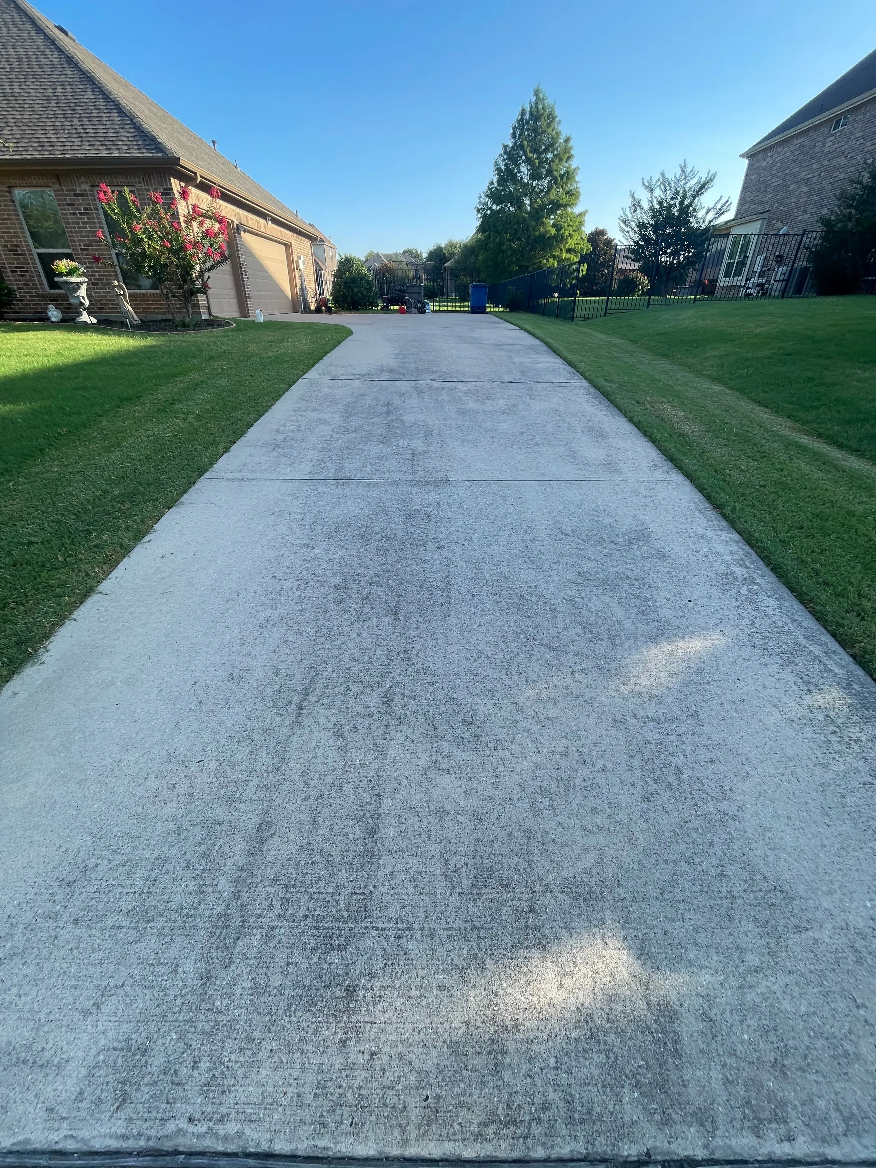 Long residential driveway streaked with dirt and grime before pressure washing in the Dallas area