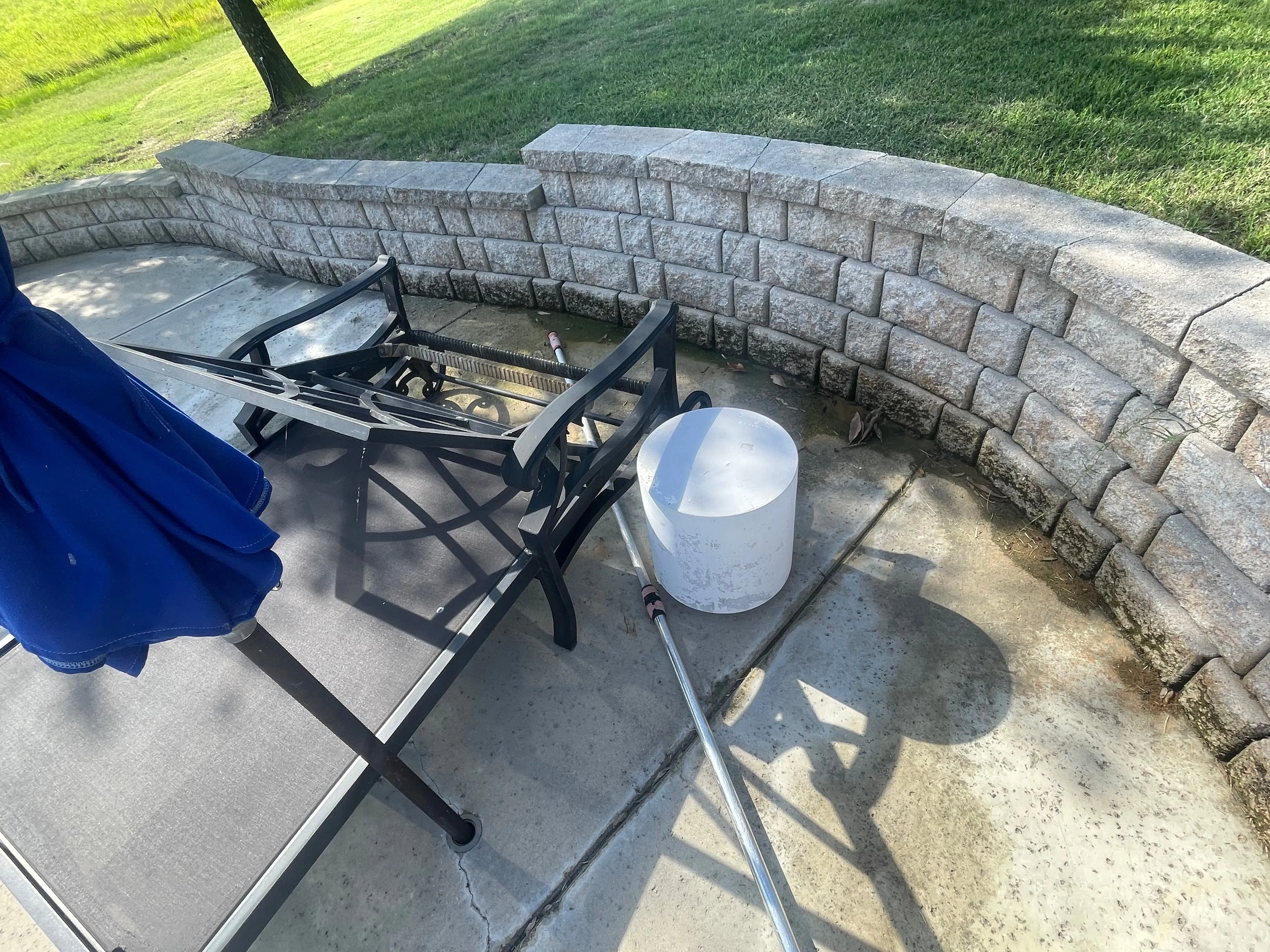 Stained concrete patio with a stone wall before power washing in Wylie, TX