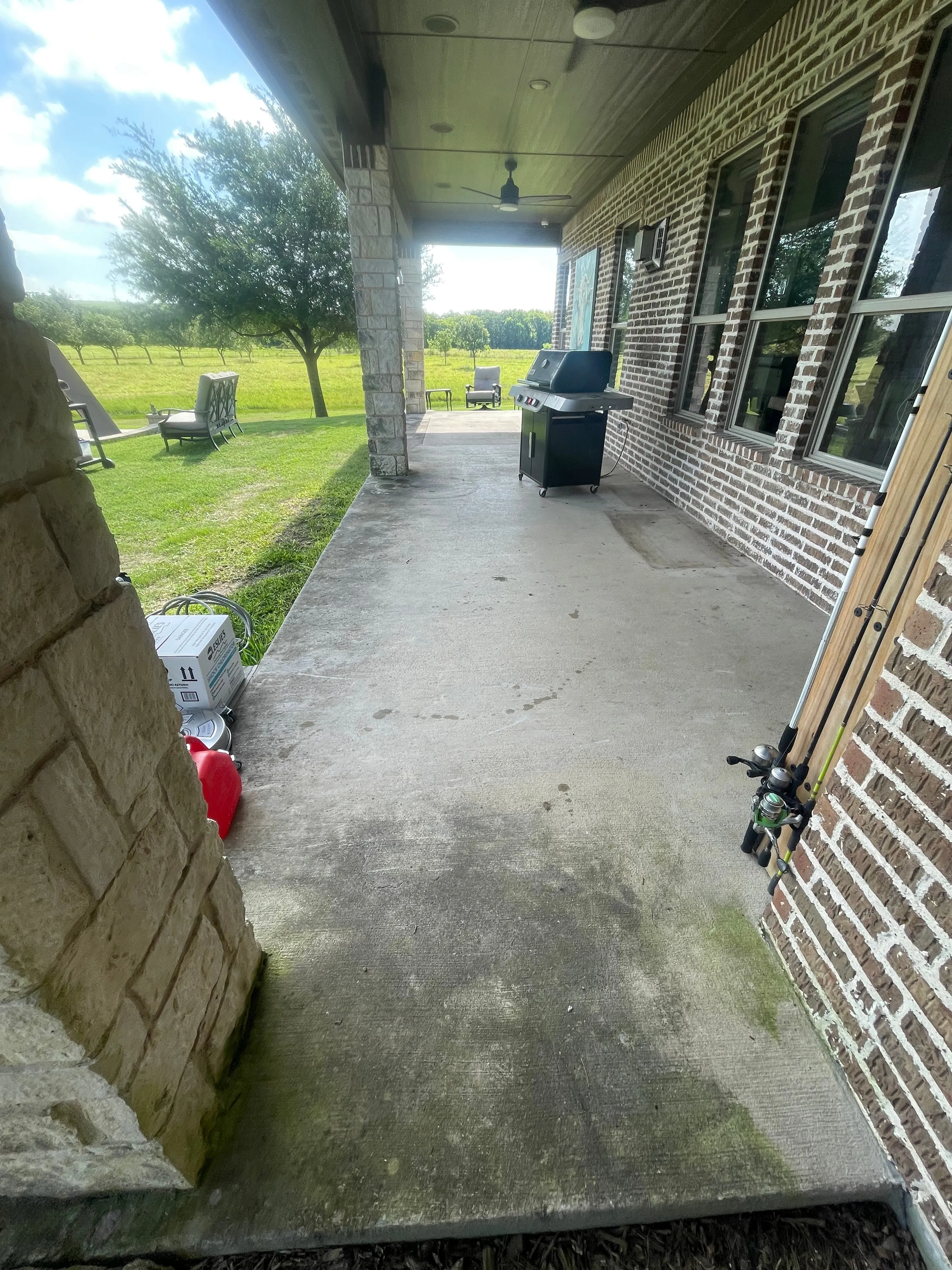 Covered side patio with algae-stained concrete before power washing in Wylie, TX