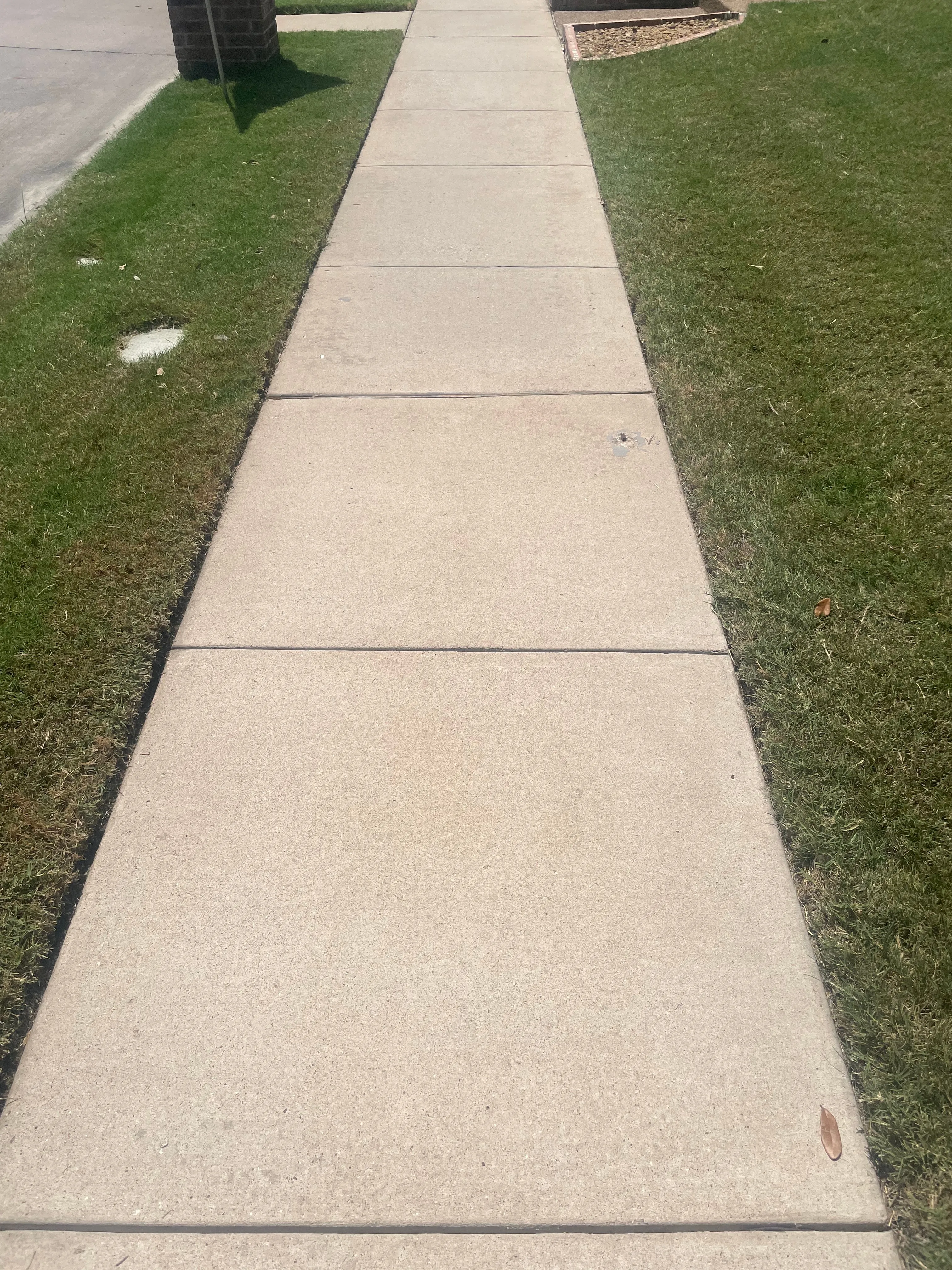 The same sidewalk cleaned to bright, even concrete after pressure washing in the Dallas area